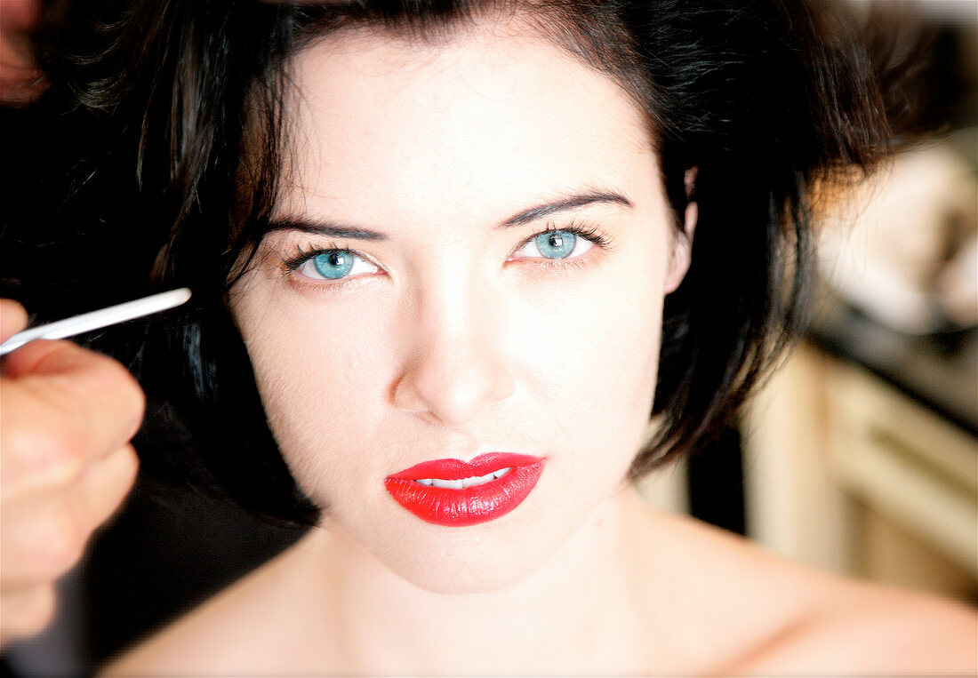 Portrait of pretty blue eyed woman with dark hair and pale complexion in red lipstick 