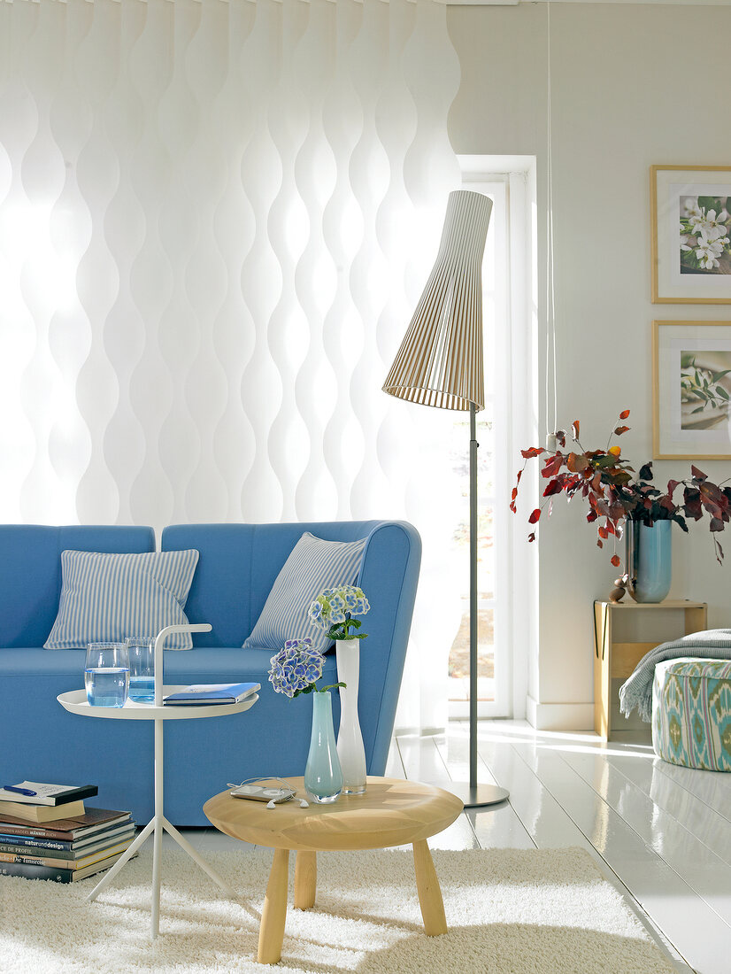 Living room with blue sofa in front of white slat curtain