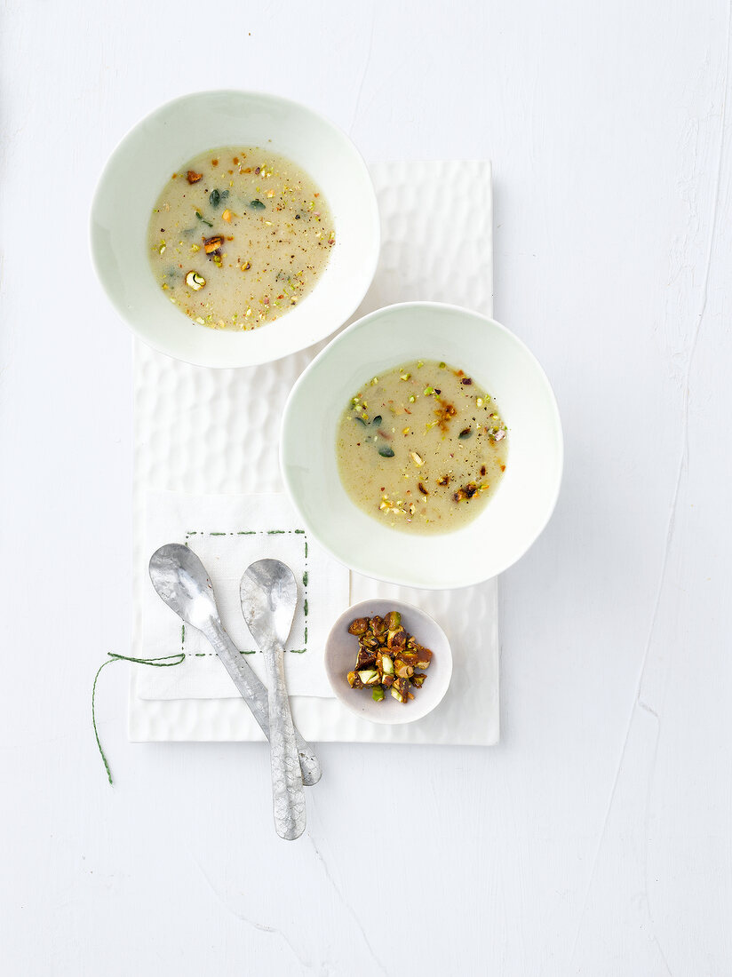 Two bowls of pistachio soup with chestnuts, overhead view