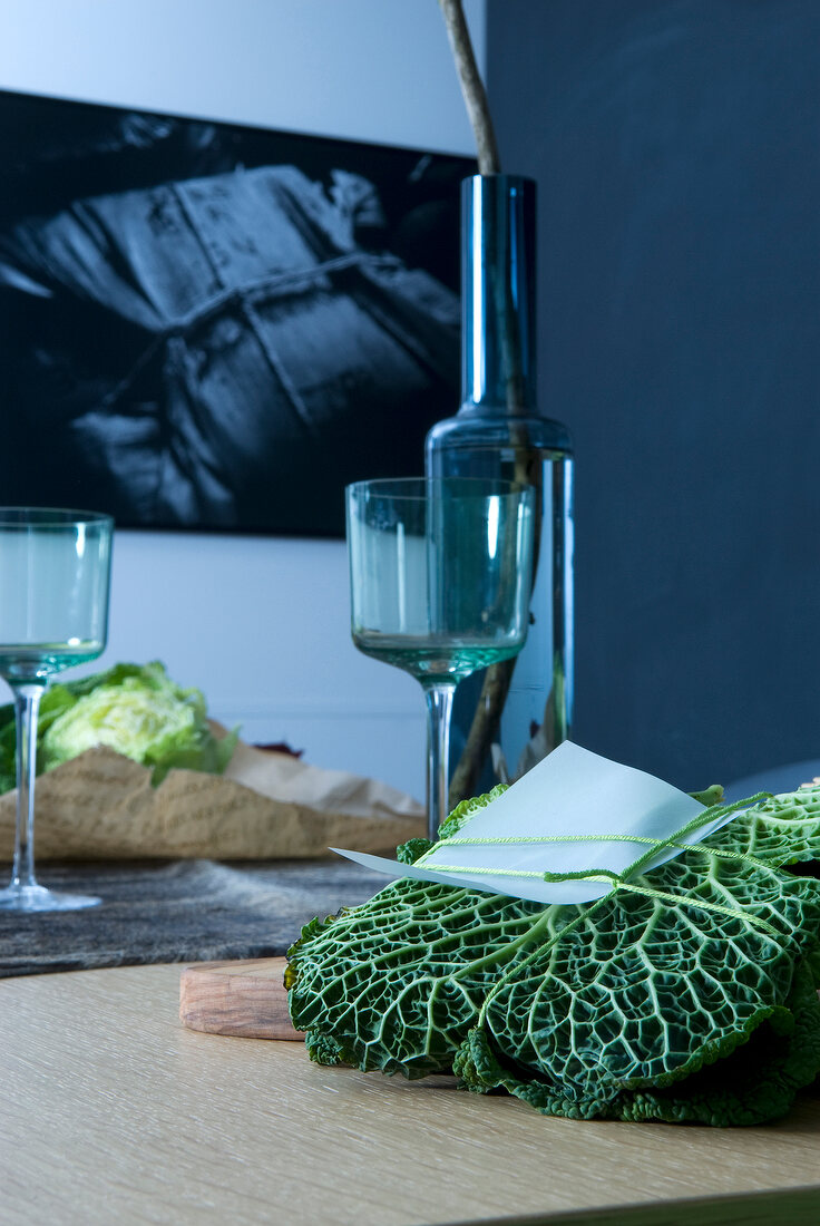 Close-up of gift wrapped kale leaf, wine glasses and bottle on table