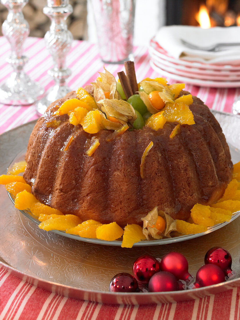 Savarin with orange segments, physalis and cinnamon sticks in bowl