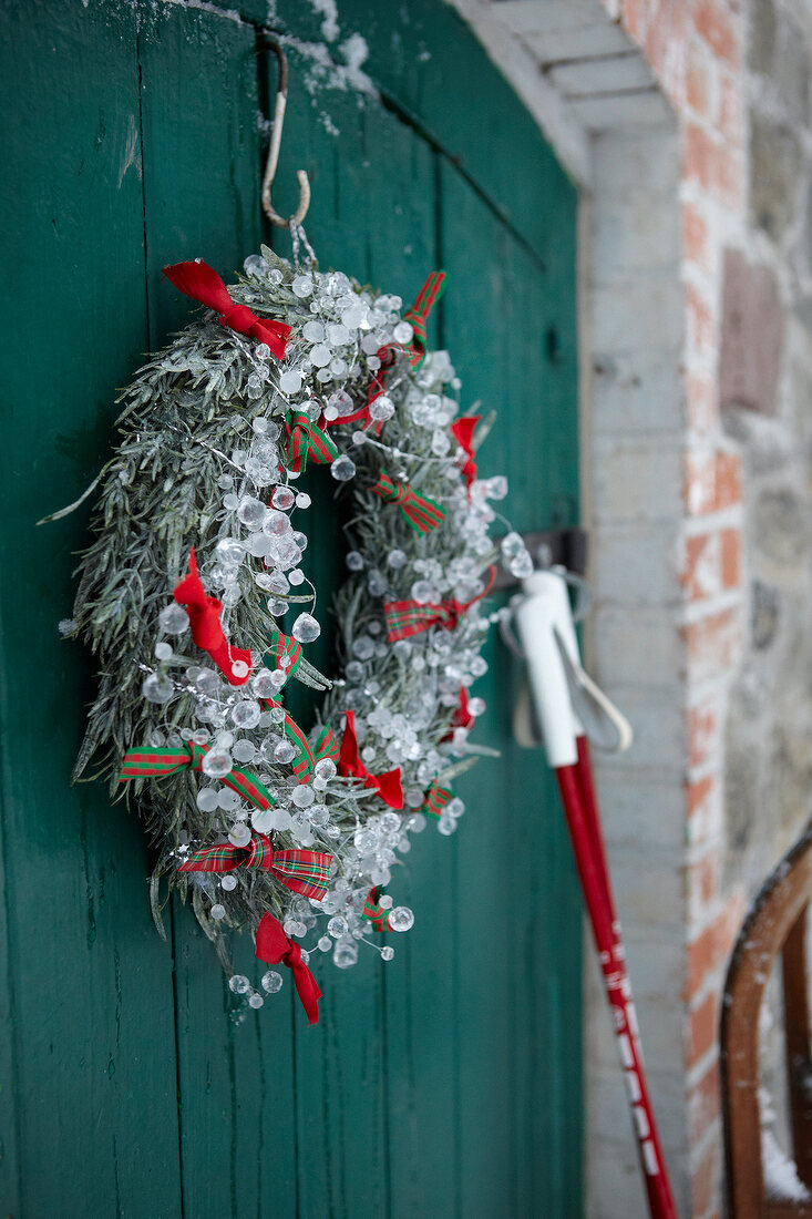 Close-up of Christmas wreath decorated with glass beads on green wooden wall