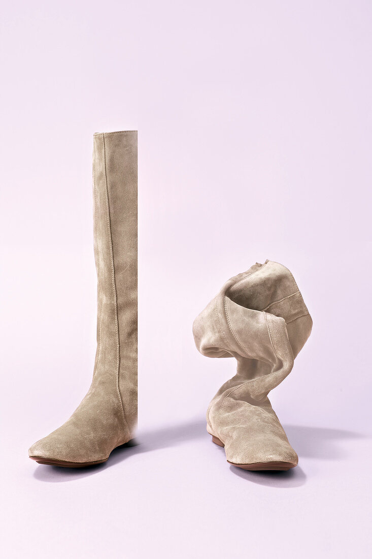 Beige suede boots on pink background