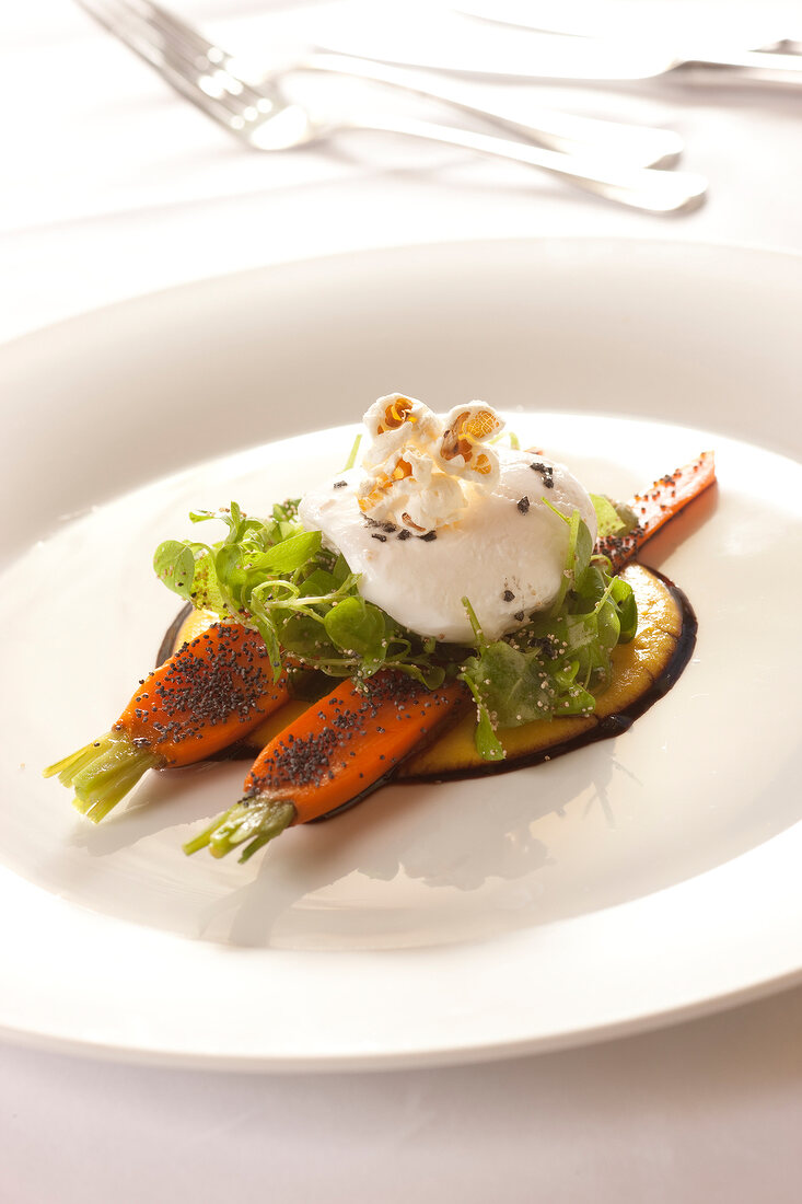 Close-up of carrots with poppy seeds and poached egg on plate