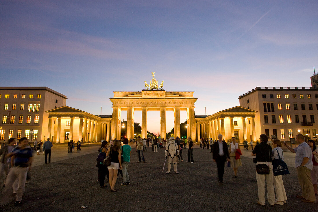 People at illuminated Brandenburg Gate and Pariser Platz at dusk, Berlin, Germany
