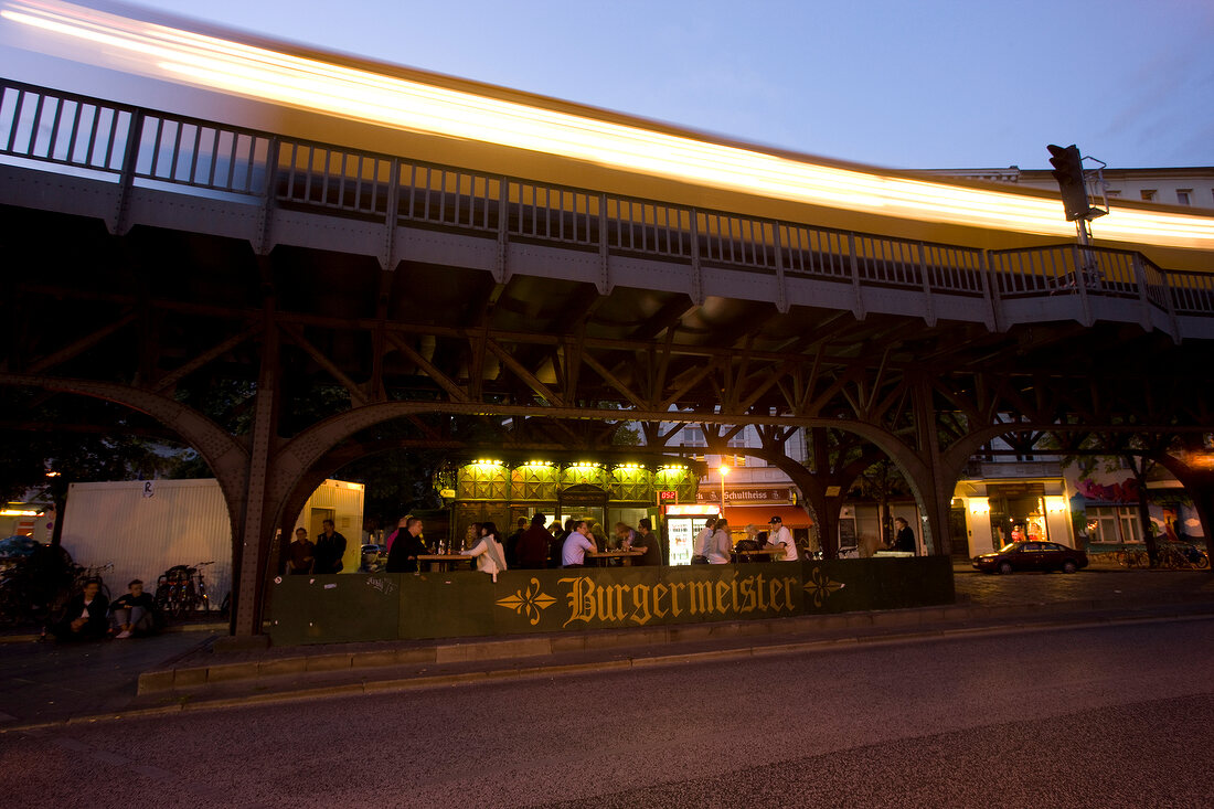 People dining at Burgermeister under bridge at night