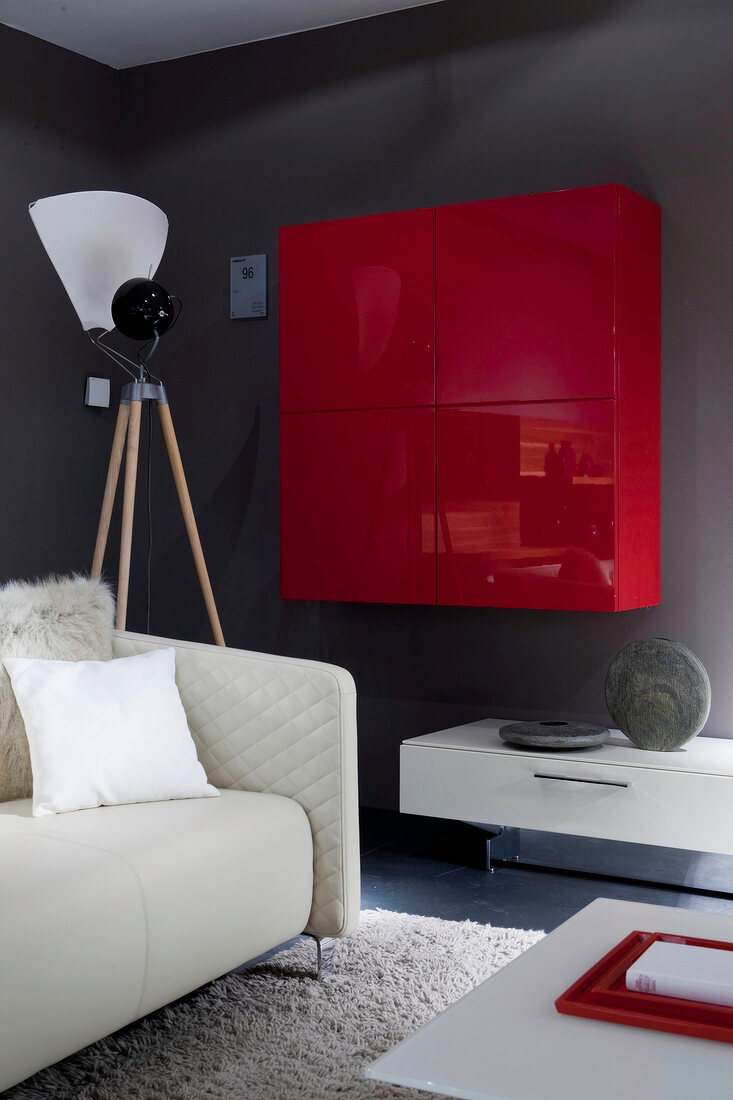 Red lilac wood wall unit on gray wall with sofa and lamp