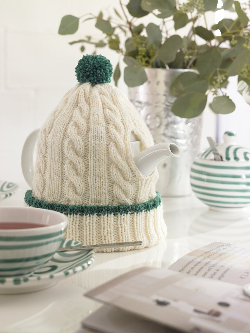 White poodle hat on teapot as warmer
