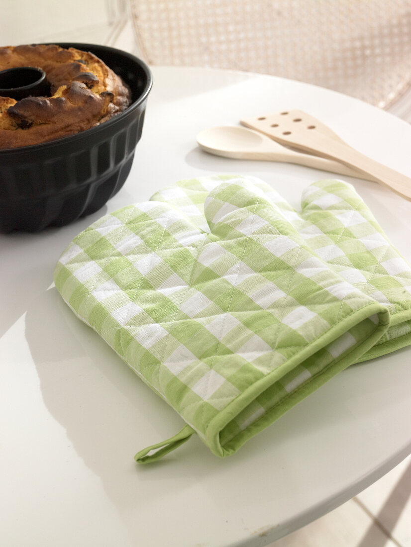 Green and white gingham oven gloves on table