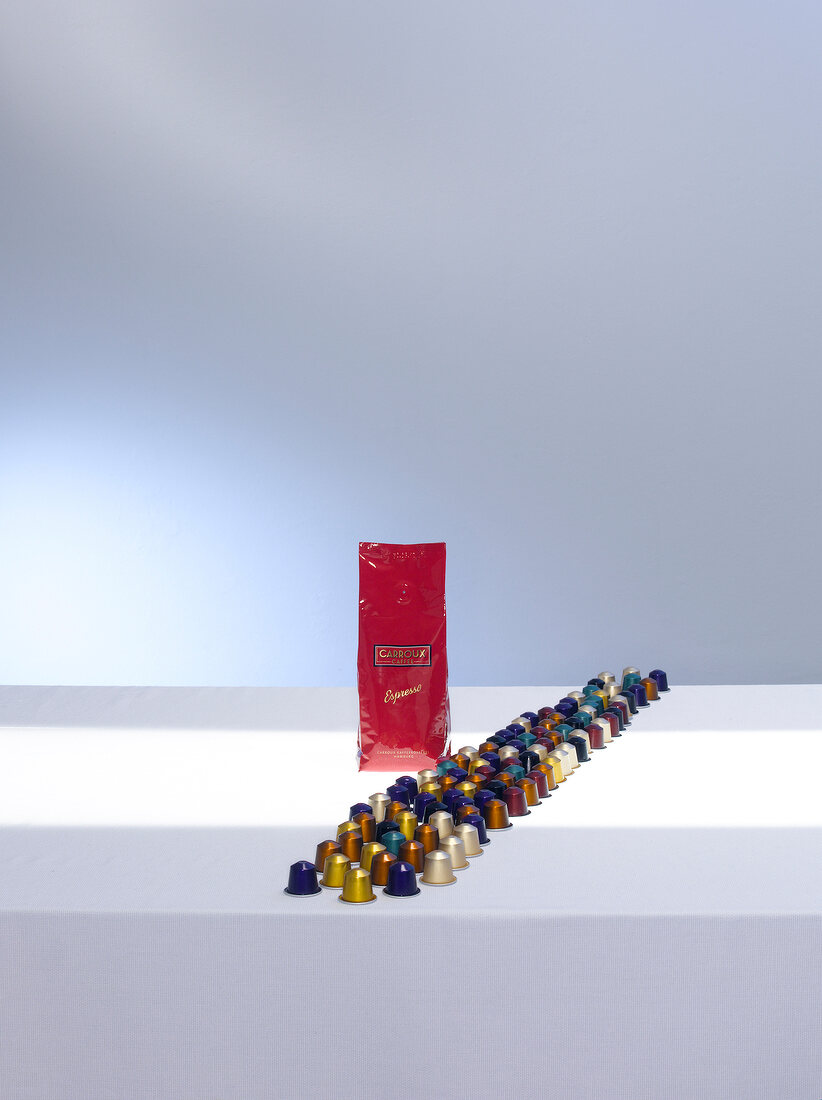 Colourful nespresso capsules arranged on table with packet of expresso coffee