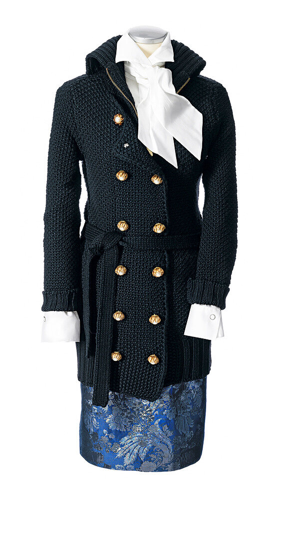Black knitted coat over white blouse and floral patterned blue skirt on mannequin
