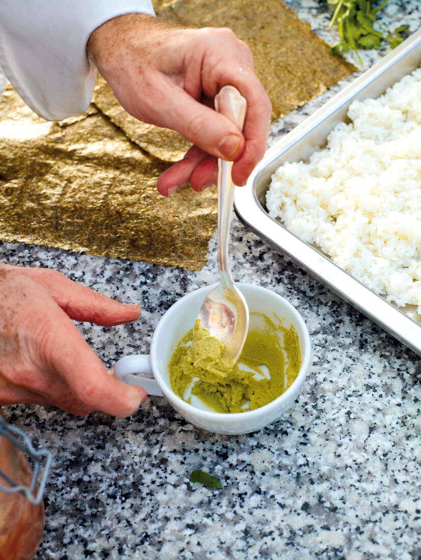 Close-up of wasabi in spoon from bowl to prepare tuna