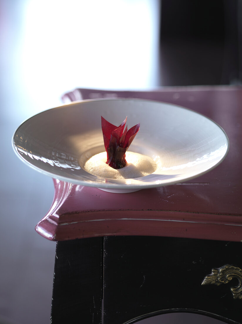 Compressed borsch with mushroom foam and beetroot leaf on plate