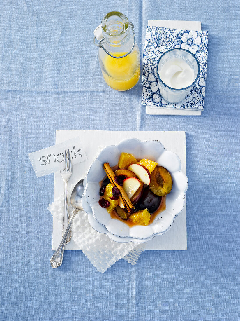 Cinnamon with orange, plum and apple slices in bowl