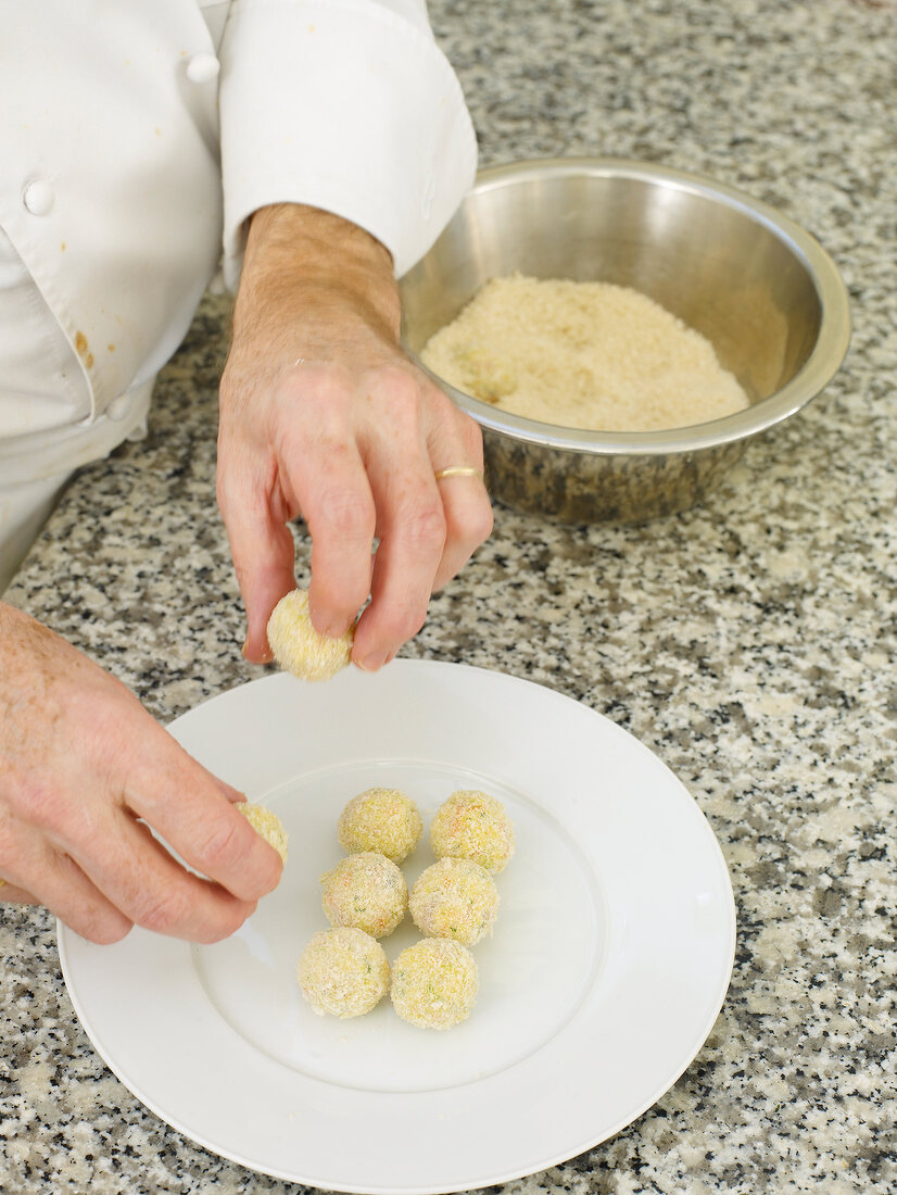 Close-up of man's hands arranging coated fried rice balls on plate