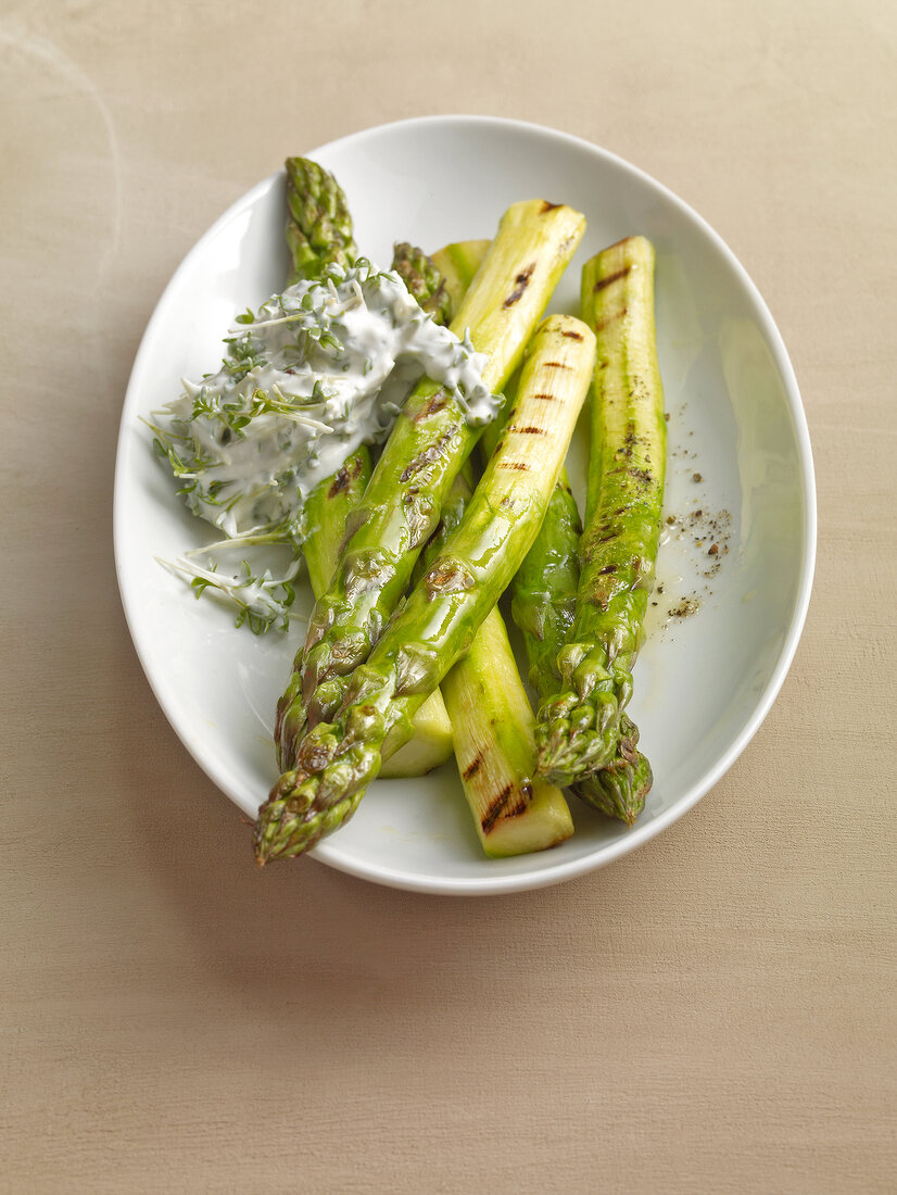 Barbecued green asparagus with goat cheese and cress dip in serving dish