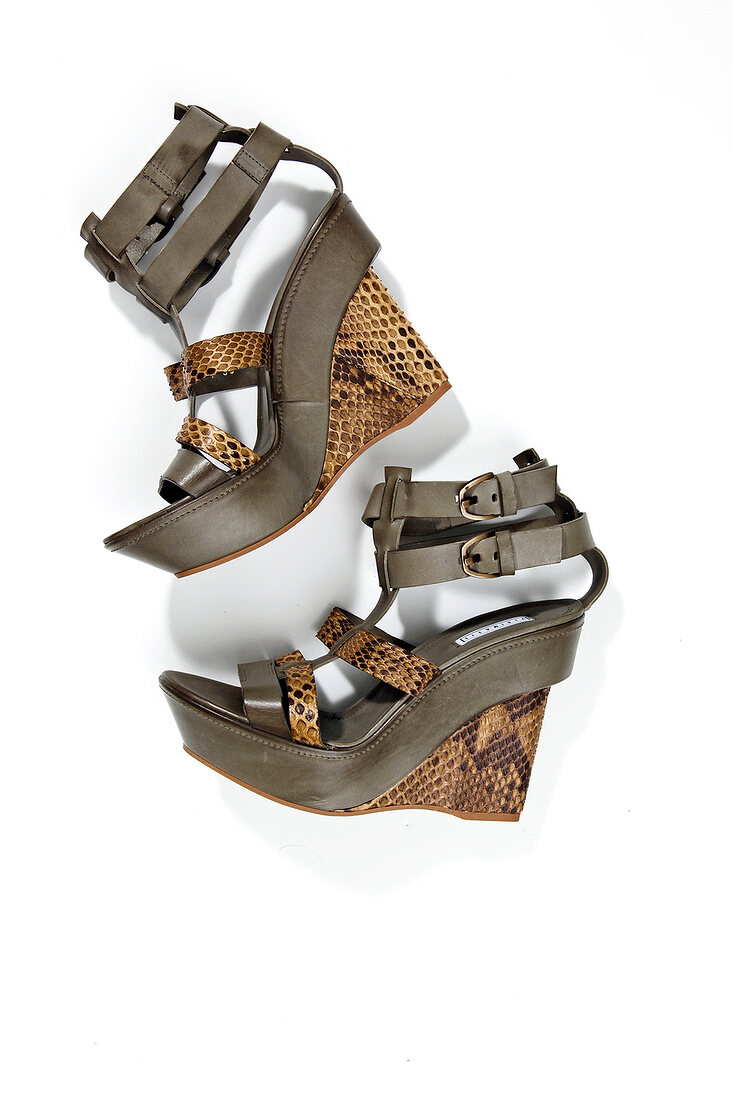 Close-up of sandals with snake patterned wedge heels on white background