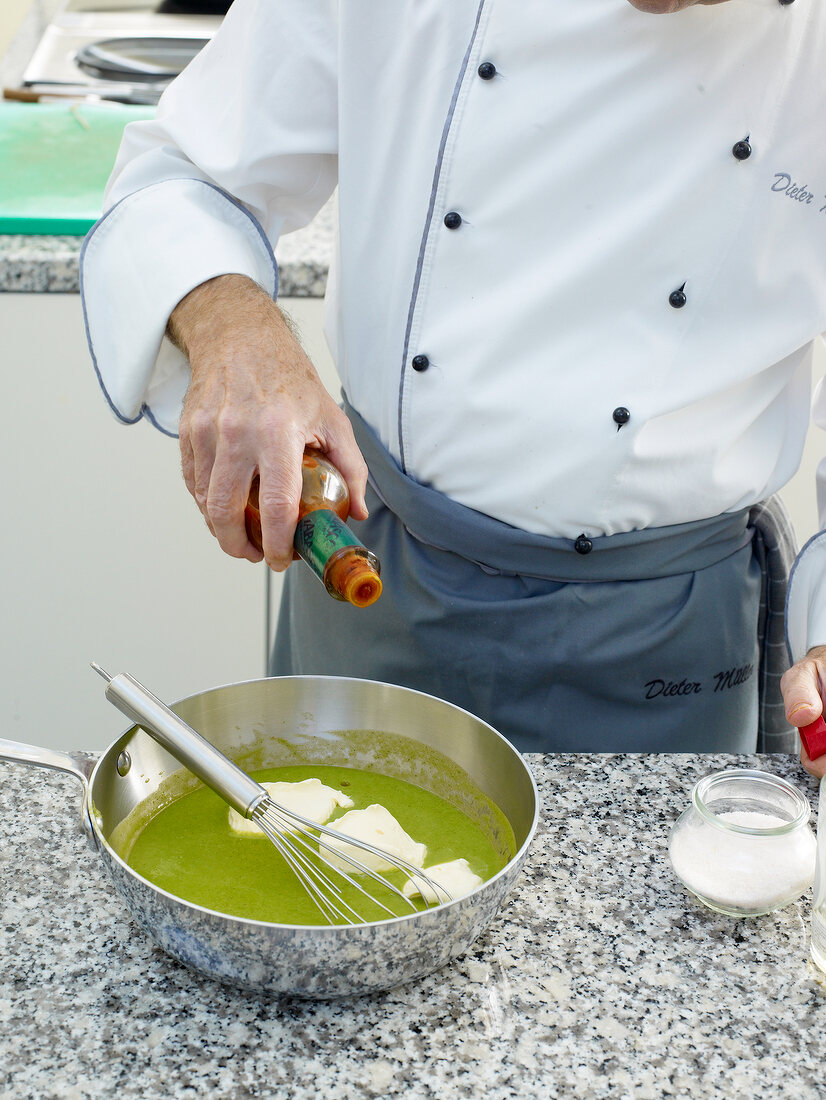 Close-up of man's hands pouring sauce from bottle in pan