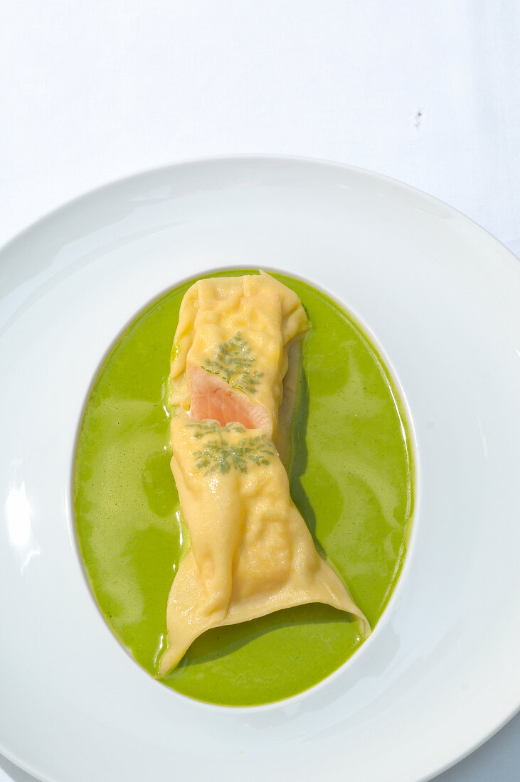 Salmon fillet in pasta with salad sauce on plate, overhead view