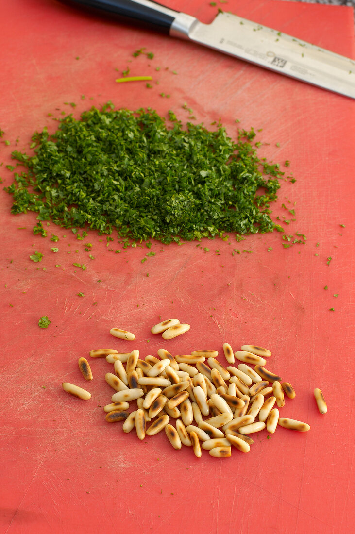 Chopped parsley and pine nuts on board