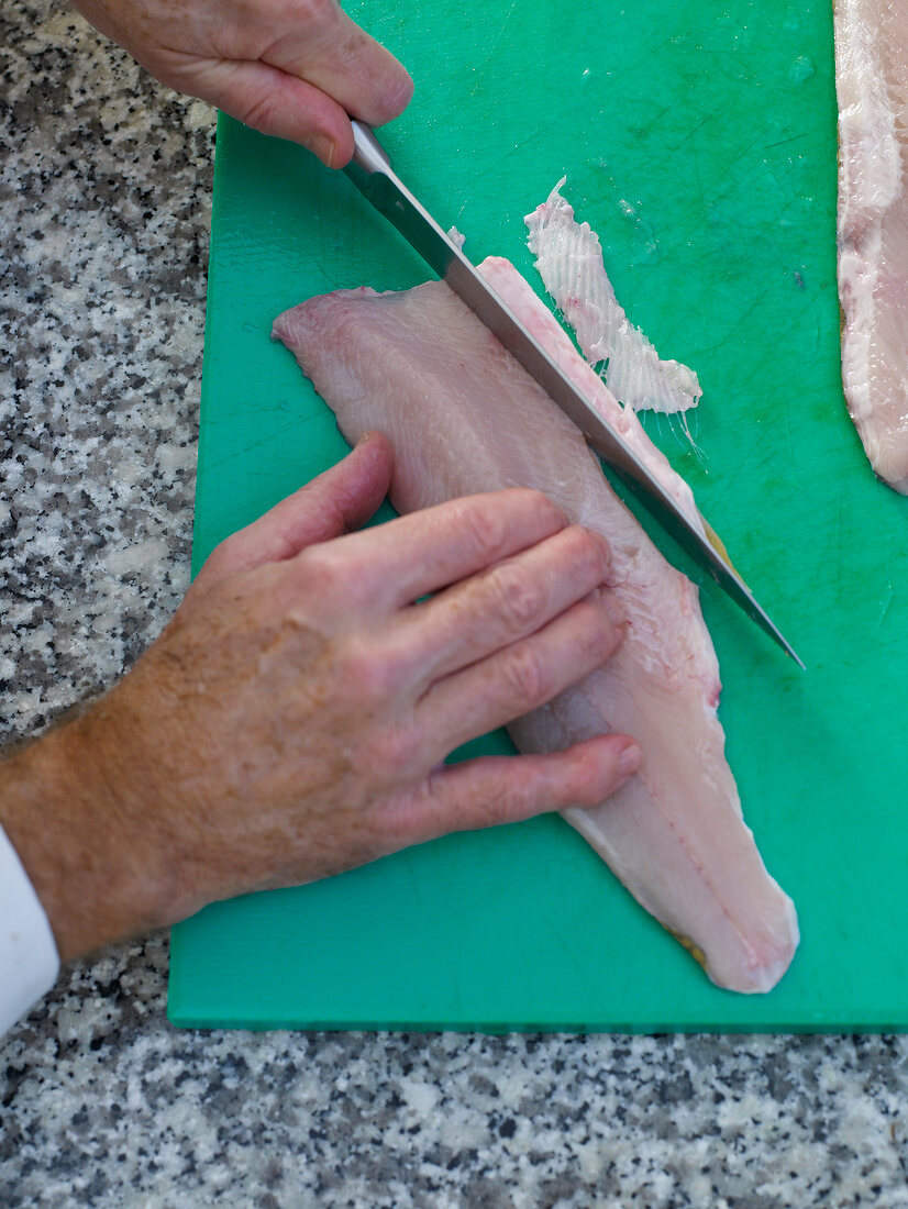Arctic char being sliced on green chopping board with knife