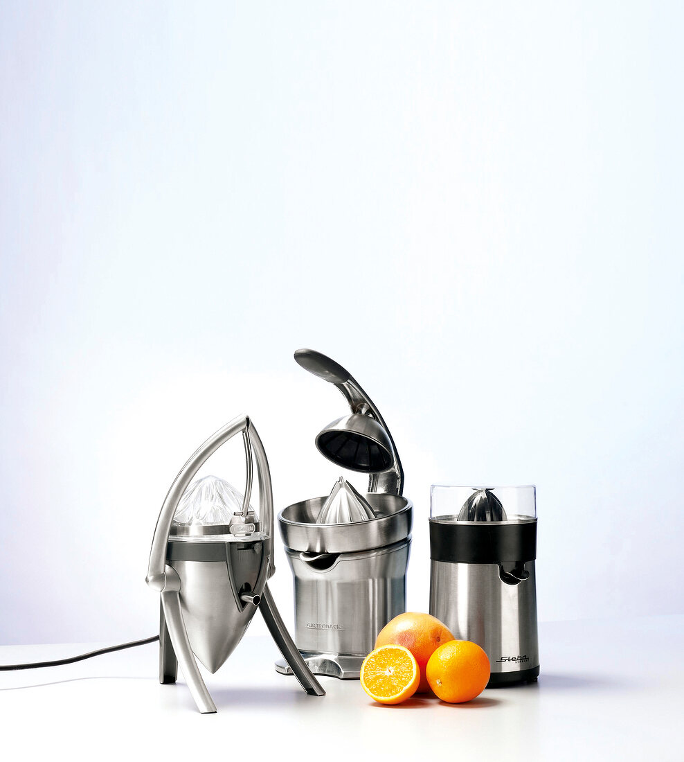 Three different juicers with fresh oranges against white background
