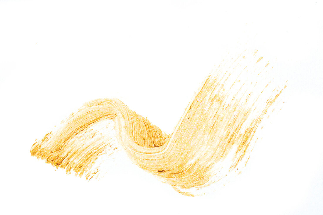 View of gold mascara smudged on white background