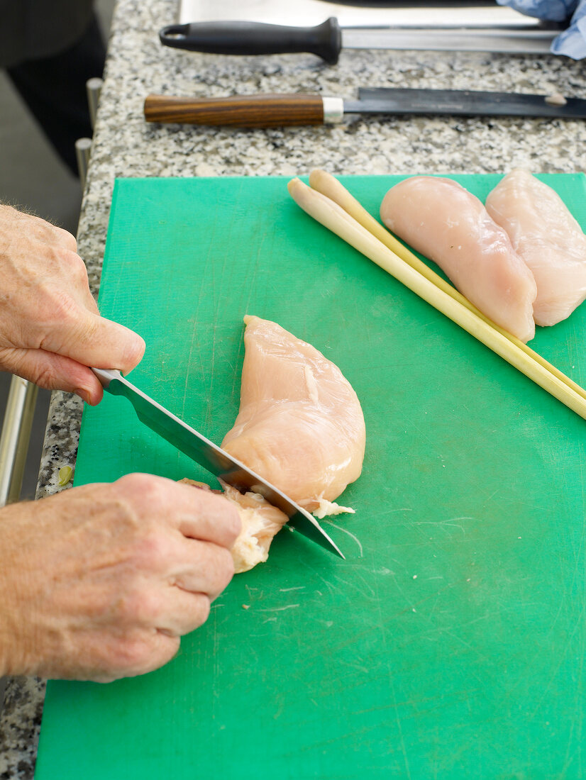 Cutting breast of chicken on cutting board