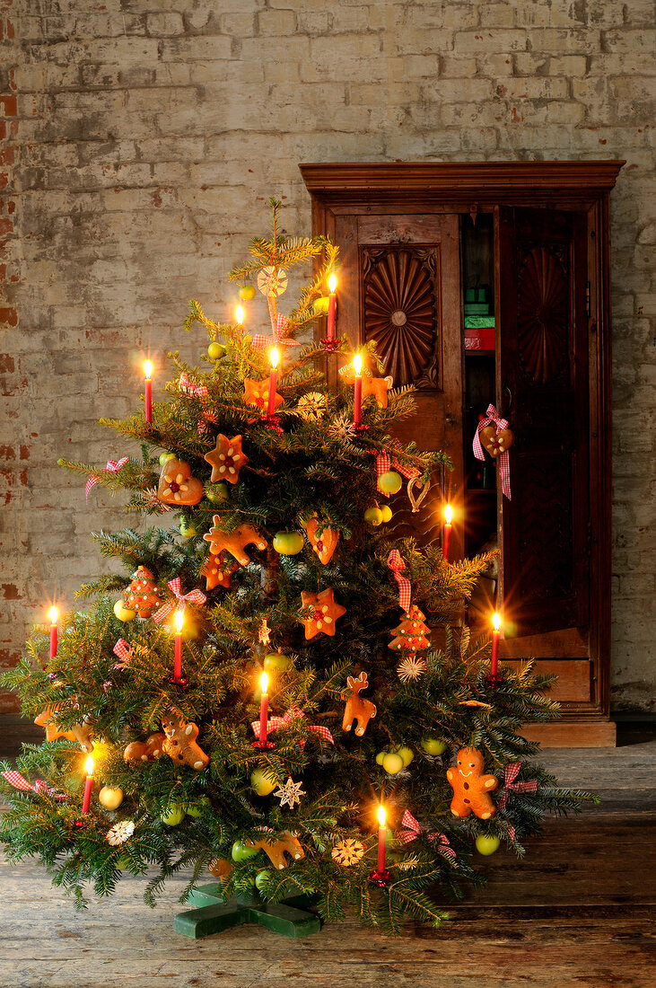 Christmas tree decorated with candles, gingerbread and small mannequins