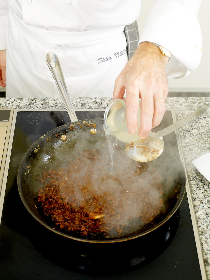 Adding lime juice to ingredients of beef sauce in frying pan