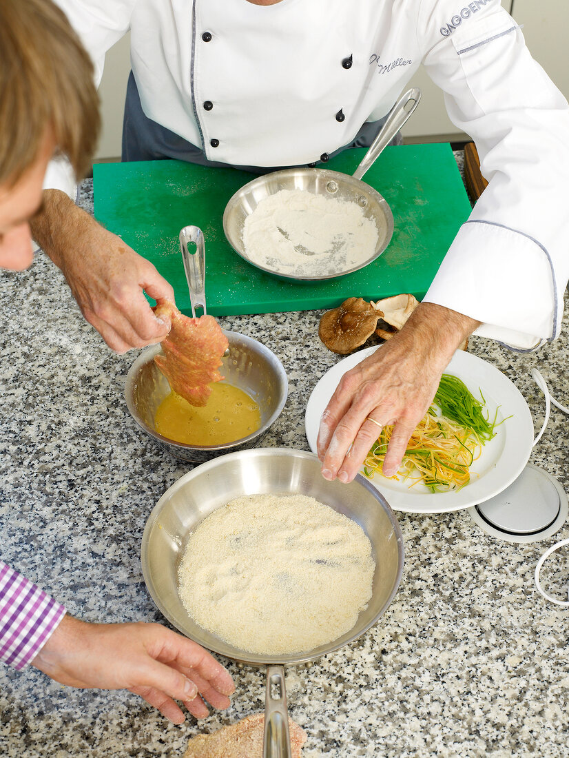 Pork being dipped in batter and flour