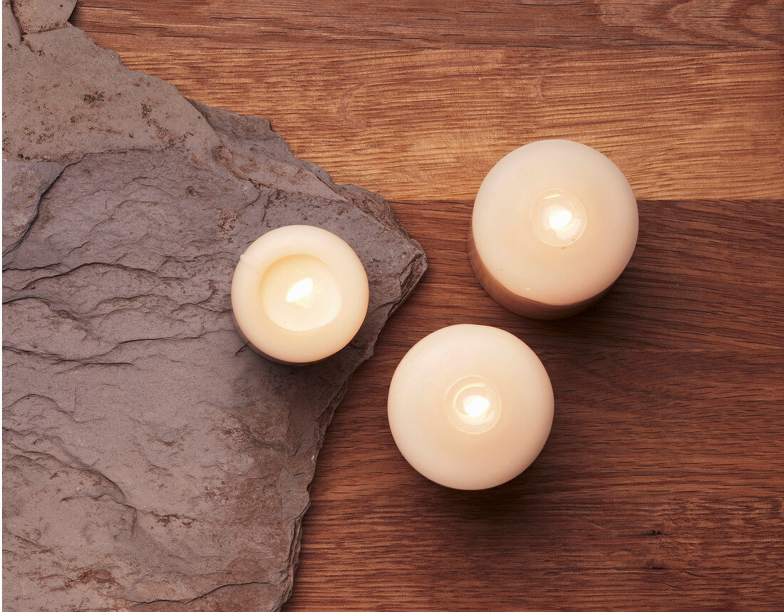 Lit tealights on wooden table, overhead view