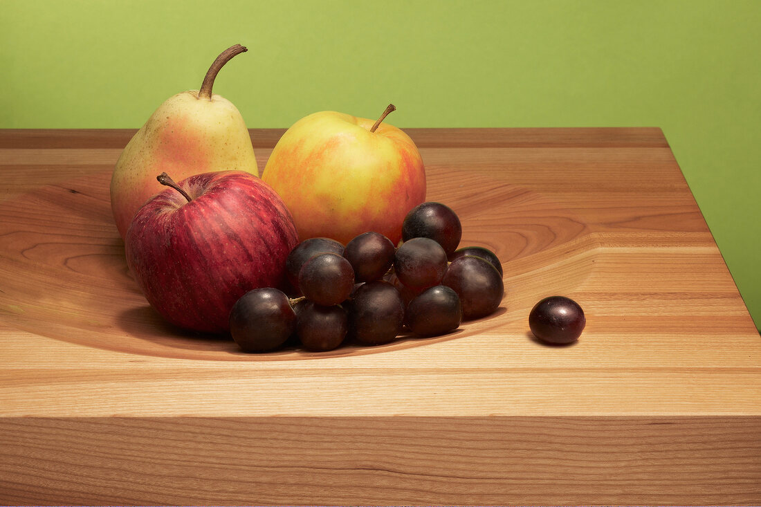Apple, peach, pear and grapes on wooden board