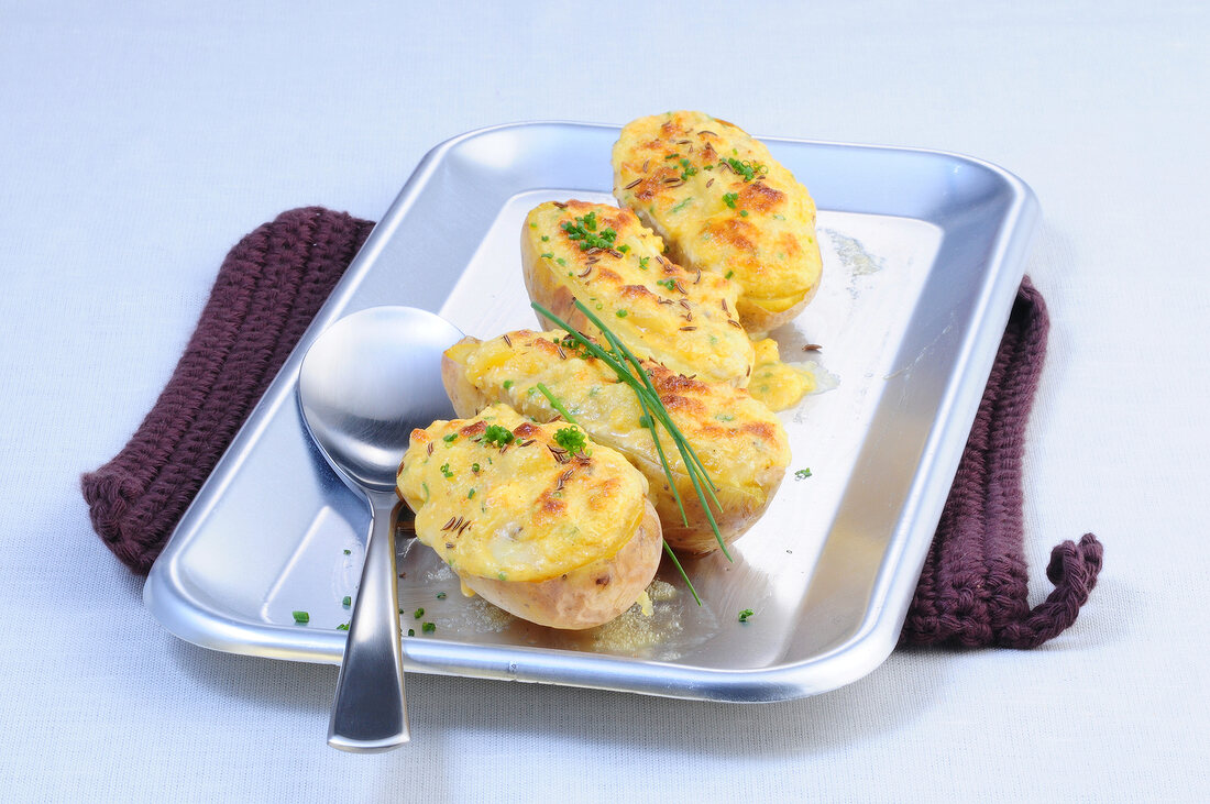Halved stuffed and baked potatoes in serving dish