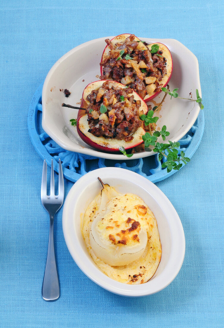 Savoury meat stuffing in apples and pears with cheese topping in bowl 