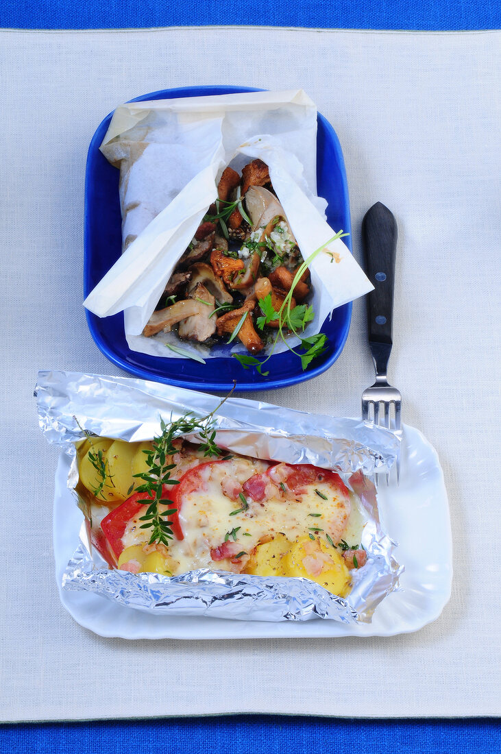 Mushrooms in parchment and raclette in foil on plate