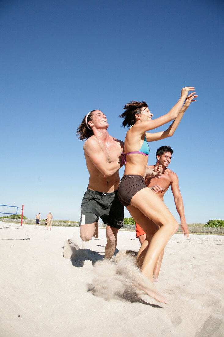 Young people playing football on beach