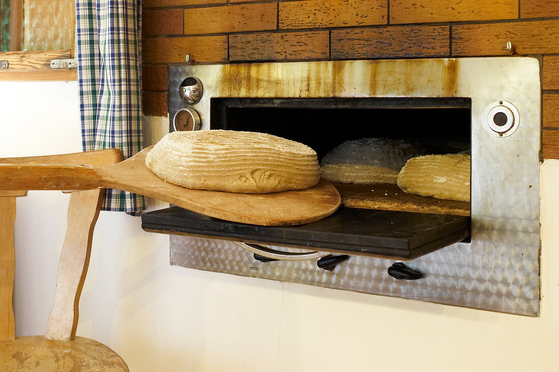 Österreich, Steiermark, Brot wird in einen Ofen geschoben