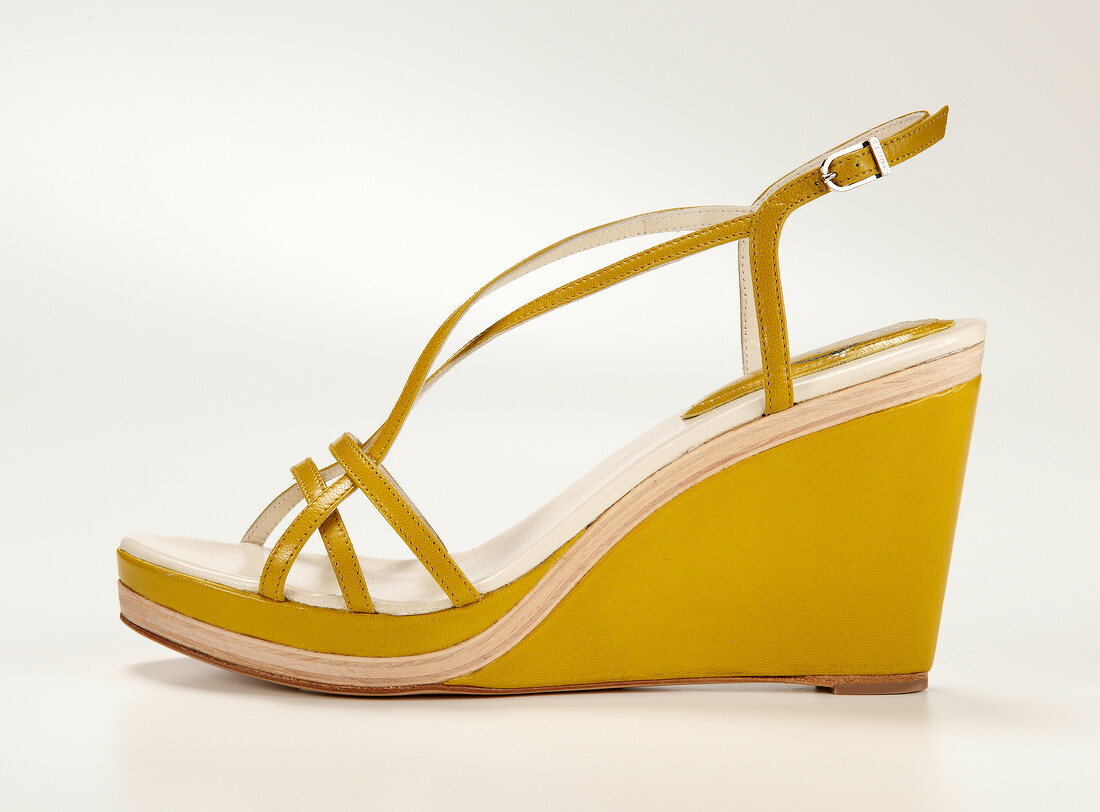 Close-up of yellow sandal with wedges on white background