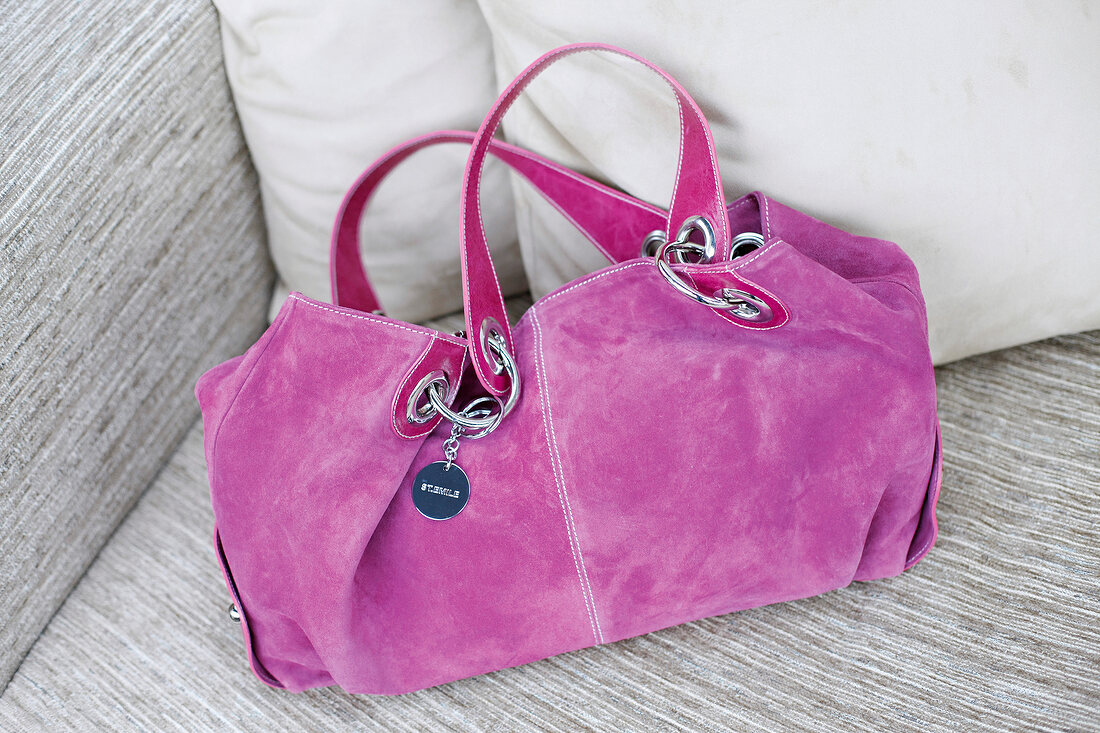 Close-up of pink suede bag on sofa