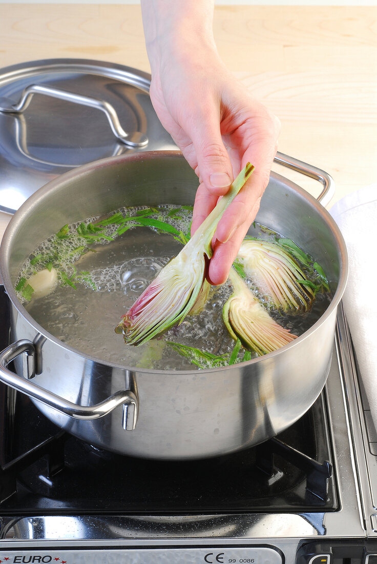 Adding artichoke in pan for preparing of artichoke salad with port wine mayonnaise, step 2