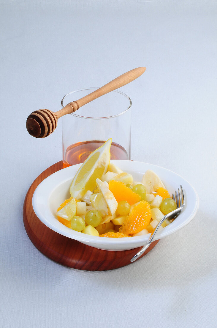 Fruit salad with honey on white background