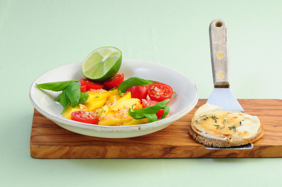 Mango salad on plate with goat cheese crostini on spatula