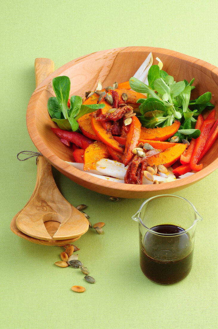 Autumn salad with pumpkin in wooden bowl