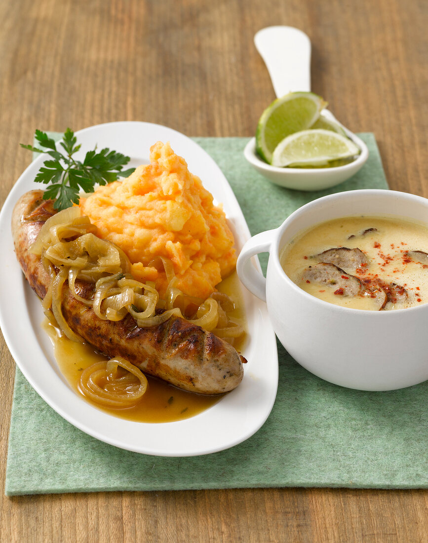 Sausage and carrot puree on plate with bowl of soup