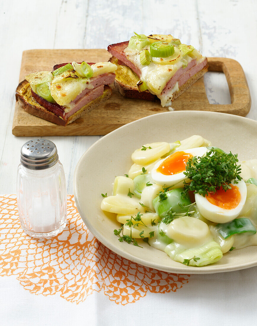 Potatoes, leeks and eggs on plate and liver with cheese on wooden board