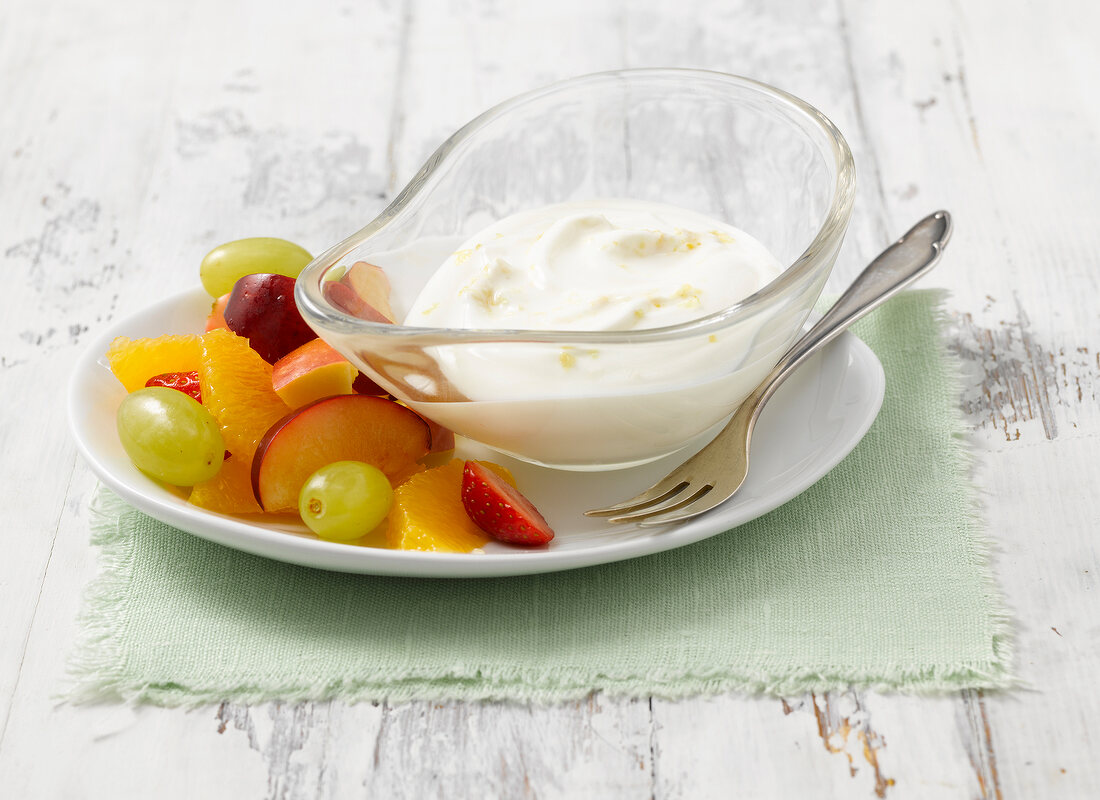 Yogurt in glass serving bowl and fruit on plate