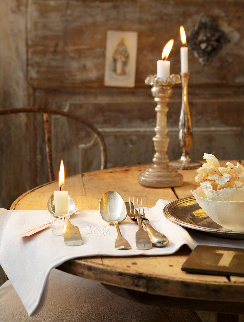 Close-up of table with cutlery, plates and lighted candles