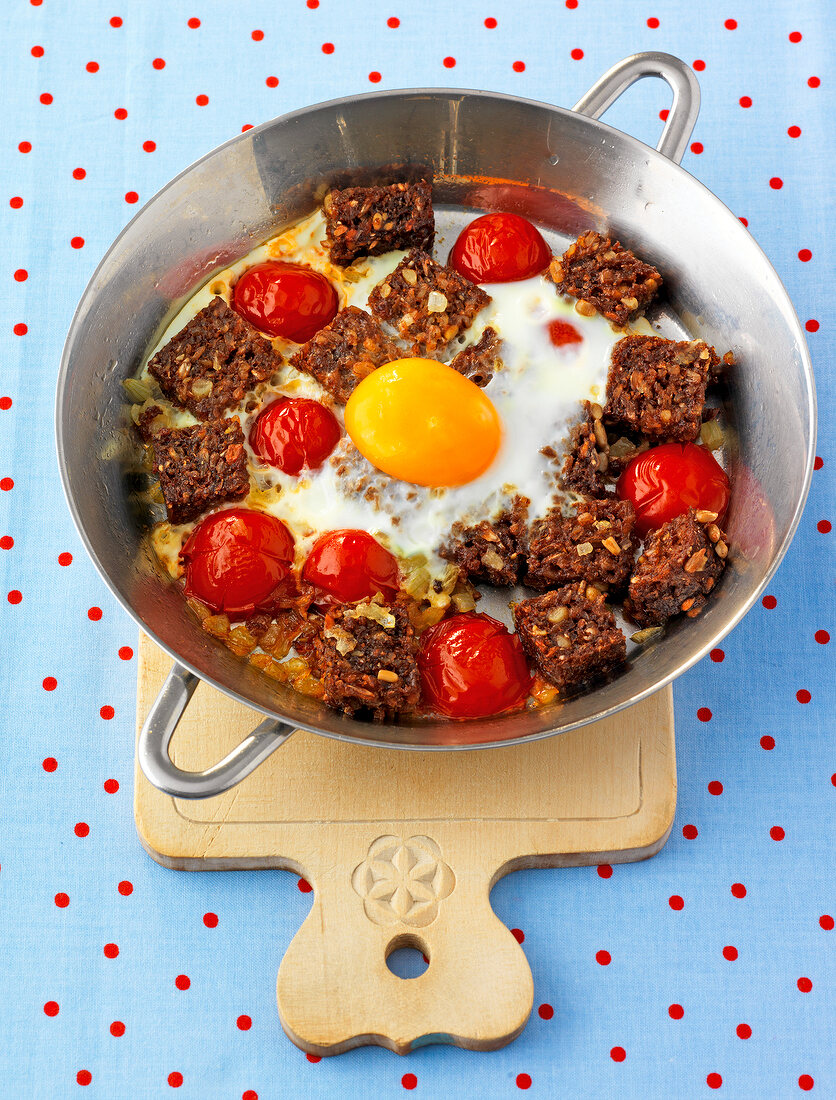 Tomatoes and eggs in wok on serving board