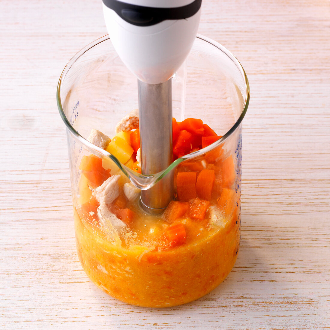 Close-up of vegetables with blended in glass jar with hand blender, step 2